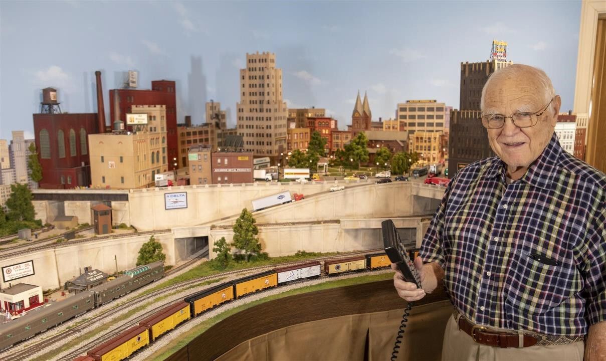 10. Bill Gibson holding a DCC controller in front of the Vining's section of his train layout.jpg